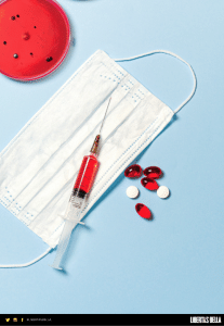 COVID-19 lockdowns - red syringe and pills laying on top of a new disposable mask